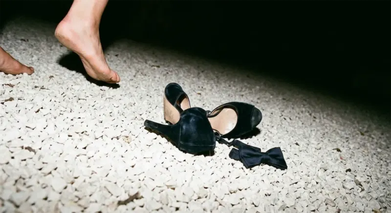 Des escarpins et un nœud papillon abandonnés sur le gravier, des pieds nus qui s’éloignent.