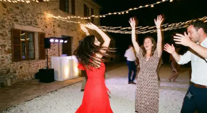 Une invitée en robe rouge tourne sur la piste, cheveux au vent, bras levés autour d’elle.